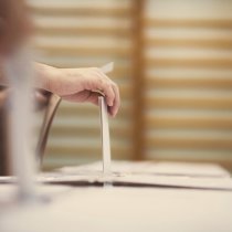 Hand of a person casting a ballot at a polling station during voting.